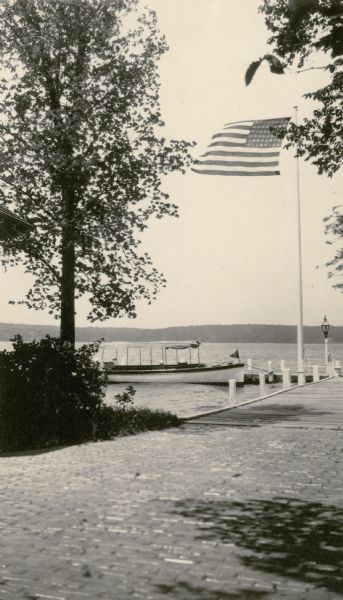 The launch "Penguin" is moored at the pier at Black Point; the United States flag is lifted by the breeze. A brick walkway leads to the pier.