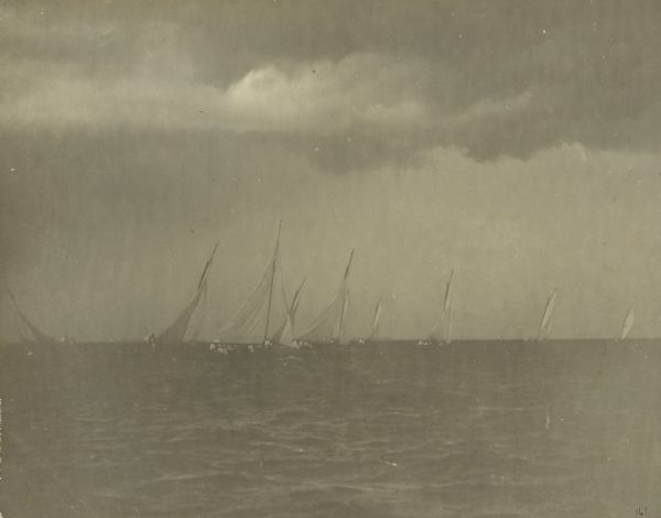 Class A sailboats race in the Inland Lake Yachting Association Regatta on Lake Winnebago just before a storm breaks. There are threatening clouds overhead.