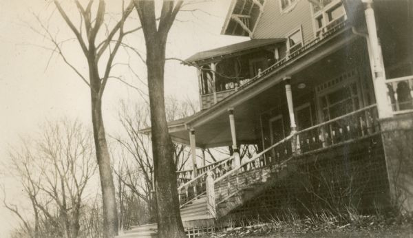 View of the front of the main house at Black Point, which faces Geneva Lake. The open first floor porch has broad steps to the lawn. There is a smaller second story porch.