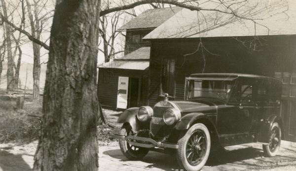 Automobile parked in front of the boathouse at Black Point. The description of the photograph written by Ernst Schmidt states, "A 1924 Loco which I just purchased; at Black Point, Lake Geneva, on April 5." Geneva Lake is in the background on the left beyond the trees.