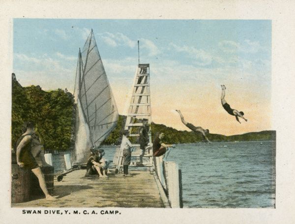 Halftone print of two divers in mid-air as other young men watch from the pier at the Y.M.C.A. camp on Geneva Lake. A sailboat is moored to the pier, which has a diving platform.