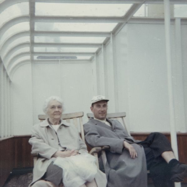 Alma Schmidt Petersen (1894-1989) sits with her son, Conrad William Petersen (1924-2013) on the Norwegian cruise ship M.S. <i>Hakon Jarl</i>. Alma is holding a plastic rain coat in her lap. Conrad's wife, Anne Reebe Petersen, and their children Barbara and Conrad Jr., were also on the cruise. Conrad, a mechanical engineer, was the General Manager, Industrial Division, Lever Brothers, New York.