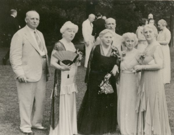 The four daughters of Conrad and Catherine Orb Seipp pose for an informal group portrait on the lawn at Black Point. The sisters are, left to right, Clara Seipp Bartholomay, Emma Seipp Schmidt, Alma Seipp Hay, and Elsa Seipp Madlener. On the far left is Clara's husband, Henry Bartholomay, Jr. Albert Fridolin Madlener, Elsa's husband, stands in the rear behind Emma. Clara holds a folding fan. The family had gathered to celebrate the fiftieth anniversary of the building of Black Point. Emma's husband, Dr. Otto L. Schmidt, and Alma's husband, William Sherman Hay, were deceased at the time of this portrait.