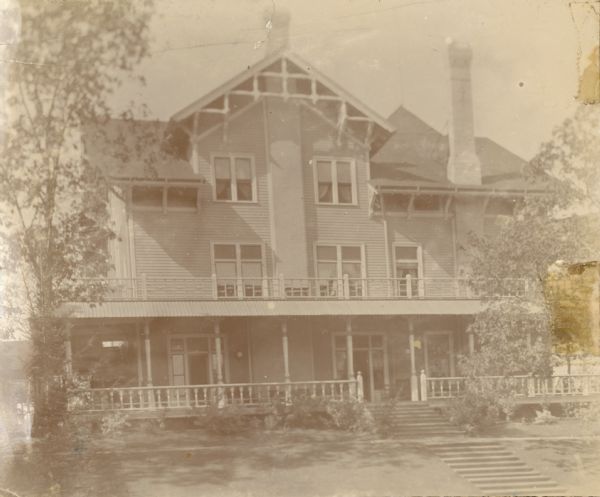 A view of the east side of the newly built Loreley, the summer home of Chicago brewer Conrad Seipp. The large, two and one half story, wood frame Queen Anne Style house has Stick Style decorative elements in the gables, two large chimneys and a porch across the entire width of the house.  The combined door and windows on either side of the chimney opened into the dining room.