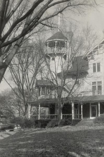 A car sits on the drive at Black Point near the distinctive tower at the northwest corner of the house. The trees have lost their leaves.