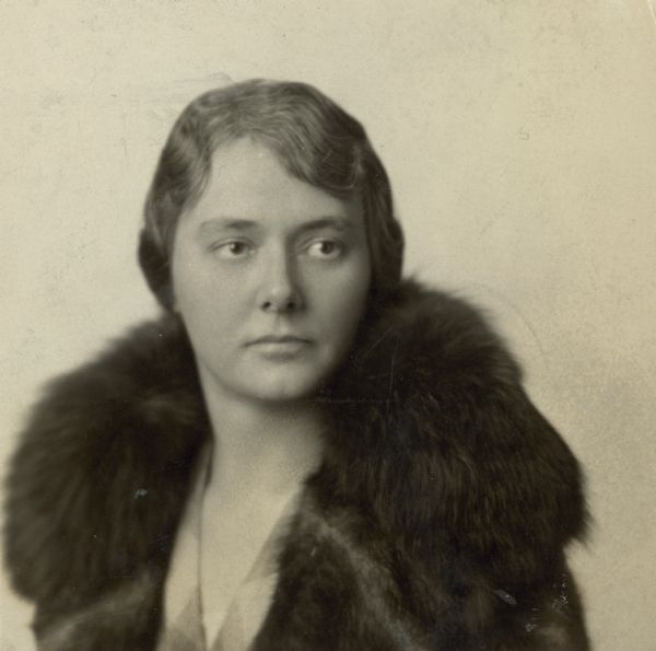 Head and shoulders portrait of Alma Schmidt Petersen wearing a fur coat. Her head is turned to her left as she glances over her left shoulder.
