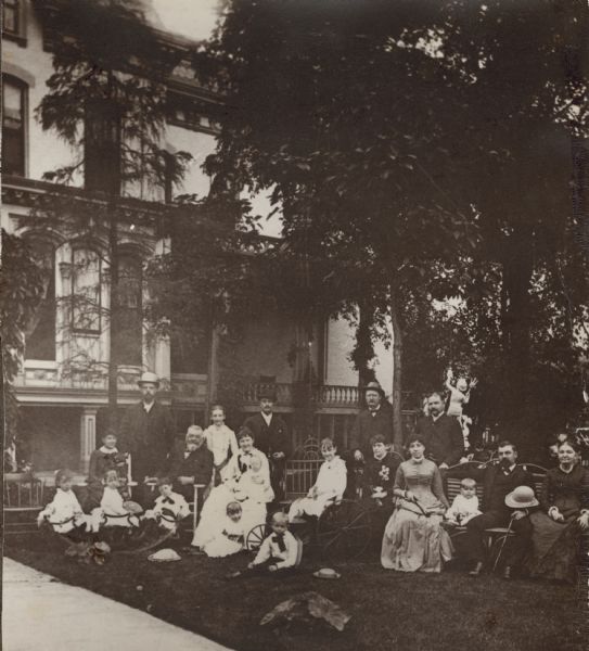 Chicago brewer Conrad Seipp (1825-1890), seated at left, poses with his second wife, Catherine Orb Seipp (1846-1920), seated to his left, with other family members outside their residence at 2730 South Park Avenue.  Pictured in the front row, from left, are Meta Lefens; Elsa Christoph and Conrad Christoph, on teeter-totter; Alma Seipp; and Philip Seipp.  In the second row are Marie Lefens; Conrad Seipp; Catherine Orb Seipp holding her youngest child, also named Conrad Seipp; Elsa Seipp on tricycle; Hattie Seipp Christoph; Emma Huck Seipp (the wife of William Conrad Seipp); Edwin Seipp; William Conrad Seipp (the eldest child of Conrad and Maria Teutsch Seipp);  and Mrs. Huck.  Standing, from left, are T. J. Lefens; Clara Seipp; a Mr. Robinson; John A. Orb; and Henry Christoph.