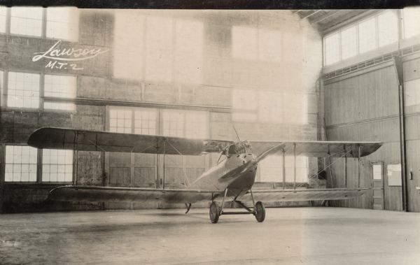 Photographic postcard of a three-quarter view from front left of a Lawson Military Tractor 2 (MT2) in a hangar.