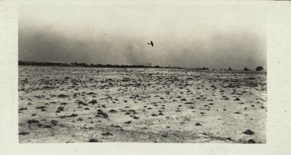 Lawson Military Tractor 2 (MT2) in flight, probably near Green Bay. View across field towards the airplane flying in the distance.