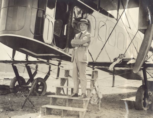 Outdoor portrait of Alfred Lawson standing on steps next to the cockpit of a Lawson Air Liner.