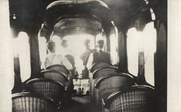 View of the interior of a Lawson Air Liner from the rear of the airplane. Four men are sitting in the front of the plane, including two in the pilot and copilot's seats.