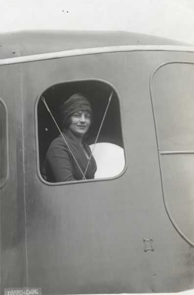 An unidentified woman is looking out of an open window of a Lawson Air Liner.