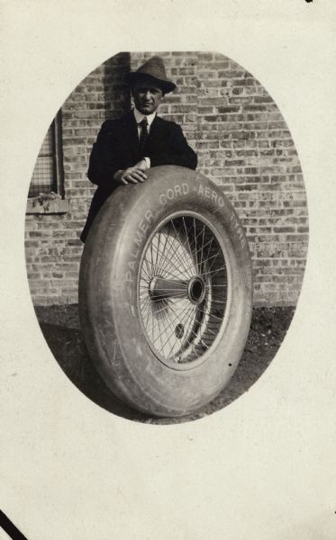 Oval-framed portrait of Alfred Lawson standing behind a Palmer cord aero tyre, which he used for his 1920 Midnight Air Liner. 