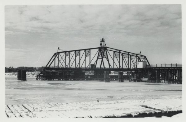 Ahnapee & Western Railway Bridge from north side of frozen Sturgeon Bay. The bridge is made of wood (and steel supports???). There is a dock in the foreground.