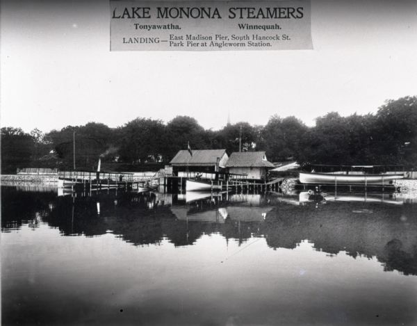 View from water towards shoreline of Lake Monona steamers "Tonyawatha" and "Winnequah" moored at the Angle Worm Station pier. There is a man standing in each steamer. On the right is a man in a rowboat. The Angle Worm Station was located at the end of S. Carroll Street. There were other excursion stations at S. Hancock Street and, later, at Waunona Way.

