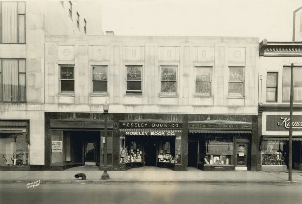 View across street towards the Moseley Book Company, at 10 E. Mifflin Street. The storefront is below the offices of Central Life. Next door on the right are the Royal Tailors Inc. and Kinney Shoes.