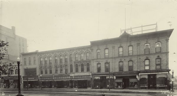 View across street towards the row of first floor businesses on S. Pinckney Street. From left to right: S.S. Kresge Co.; Wolff, Kubly and Hirsig Co. Hardware; Moseley Book Co.; Schumacher's Shoes; Mueller-Simpson Company Men's Clothing; Breitenbach's Shoes; Mangel's; and H.H. Ratcliff Co. Opticians and Jewelers. On the second and third floors are signs for tailors, women's skin products, the Willett E. Main Insurance Agency, and Reierson Photographer. To the left of and behind the S.S. Kresge Company is a partial view of the First National Bank and Central Wisconsin Trust Co. By 1935 many of these businesses had moved to other locations or disappeared.
