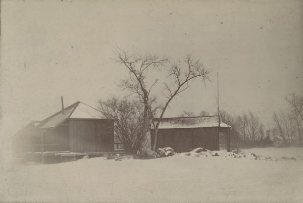 Winter view of early buildings on Rocky Roost, which was west of Governor's Island. There is snow on the roofs, on the rocks and on the shore of Lake Mendota. Frank Lloyd Wright later did a remodel of these buildings into a vacation home complex, which was owned jointly by the Robert M. Lamp and Melville C. Clark families.