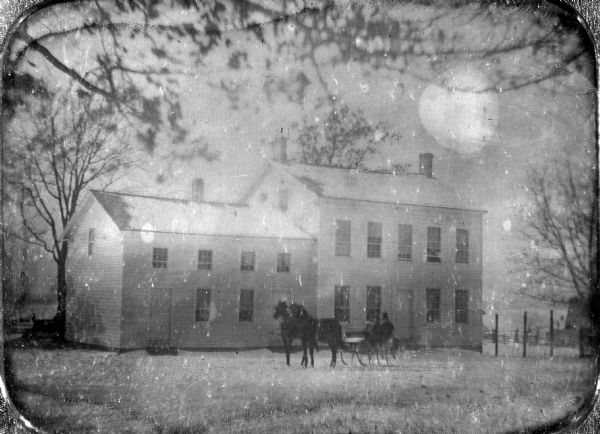 View of people riding in a horse-drawn sleigh in front of the National Hotel in a snowstorm. The National Hotel was owned by Major Eliab B. Dean. It was originally on the site of Vilas House, at Main Street and Martin Luther King Boulevard. It was moved in 1852 to Doty Street.