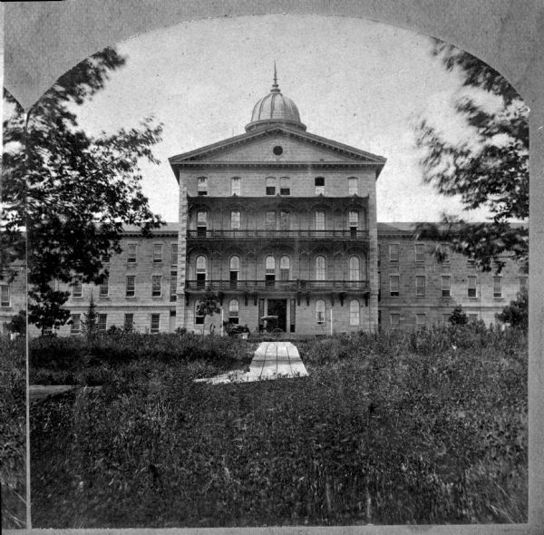 View of the Wisconsin Hospital for the Insane and grounds. In 1935 it became the Mendota State Hospital. It was built in 1860 by architect Stephen Vaughn Shipman who was commissioned to design the facility based on the Kirkbride Plan.