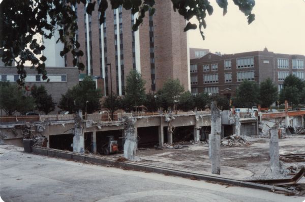View across sidewalk towards the razing of Manchester's Department Store at 14 E. Mifflin Street. The foundation is exposed. The Concourse Hotel is in the background.