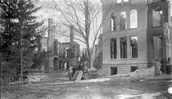 Group of people standing near two buildings which burned in 1893. In the center background is Edgewood Villa, a home purchased by Governor C.C. (Cadwallader) Washburn in 1873. On the right in the foreground is an uncompleted building intended to become the new Edgewood Academy.