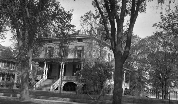View from street towards the Reverend F.F. Ford house, at 1023 Spaight Street. The house was built by Mr. Harris prior to 1875 when it was purchased by Storer. Winifred Ford, widow of Marcus Ford, lived here. Lake Monona is in the background.