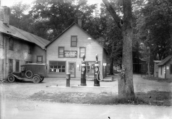 Gas pumps at the Edwards Park Hotel. A sign on the building behind the pumps reads: "Edwards Park Hotel, Ice Cream, Groceries, etc., Boats for Rent." There is an automobile parked on the left. In the background on the right are cabins and another automobile under trees.