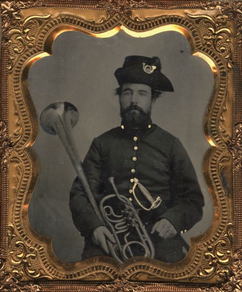 Sixth plate tintype/ferrotype of a waist-up seated portrait of an unidentified Civil War musician holding a musical horn, probably a Tenor horn in B&#9837;. Hand-colored gold details on uniform and sword have been added to the tintype.