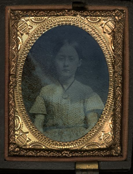 Ninth plate ferrotype/tintype waist-up portrait of a young girl. She is wearing an off-the-shoulder polka dot dress with short flared sleeves, and a ribbon necklace with pendant. Hand-coloring on cheeks.

One image, top right, from a case with four individually oval framed tintypes.