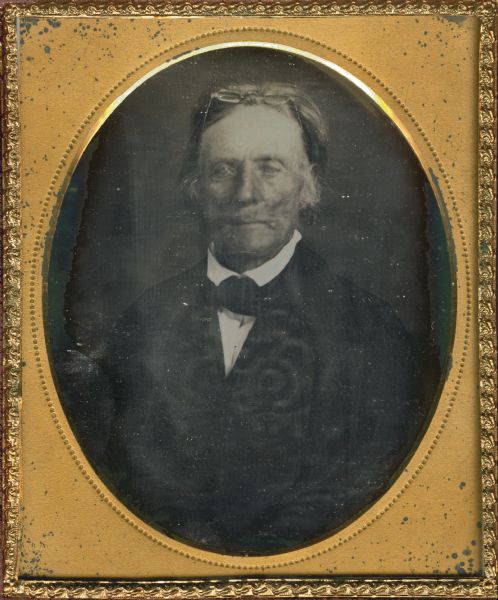 Sixth plate daguerreotype. Waist-up portrait of John Carr wearing a dark suit with a white shirt and dark necktie. A pair of eyeglasses are resting on the top of his head.