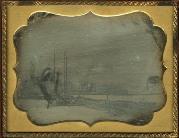 Quarter plate daguerreotype of the Oshkosh harbor, showing the bridge over the Fox River and several moored sailing vessels.