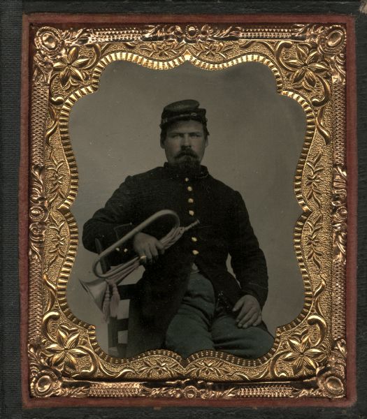 Sixth plate tintype/ferrotype of an unidentified soldier from the 13th Wisconsin Infantry. He is sitting in a chair holding a horn in his right hand. Hand-coloring of cheeks and military uniform, and gold details on buttons and a ring on his right hand.