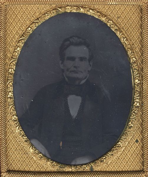 Sixth plate ferrotype/tintype of Charles Minton Baker. Baker was a lawyer, politician, b. New York City. He attended Middlebury College, Vt., studied law, and was admitted to the New York bar in 1830. Late in 1838 he moved to Wisconsin, settling at Lake Geneva, and shortly after his arrival was appointed district attorney for Walworth County. A Democrat, he served in the territorial council (1844-1846), and was a member of the constitutional convention of 1846. In 1848 he was appointed by the governor as one of three commissioners to revise the Wisconsin statutes, and in 1849 was chosen by the legislature to superintend publication of the volume. Hand-colored gold detail on watch fob.