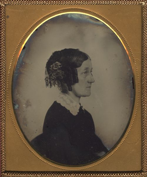 One sixth plate right profile ambrotype of Elizabeth Holt Baker. The front of her hair is styled with ringlets, and at the back is lace. She is also wearing a lace collar. 