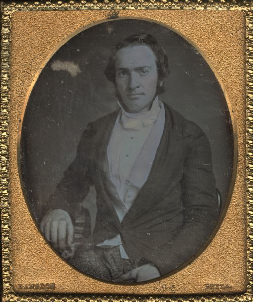 Sixth plate daguerreotype of Christian Miller of Philadelphia, Pennsylvania. Mr. Miller was the uncle of the donor of the portrait, Mrs. Julia Hicks. Half figure portrait with the subject seated and turned slightly to the left, looking front, right hand resting on prop. Hand-coloring on cheeks and vest.