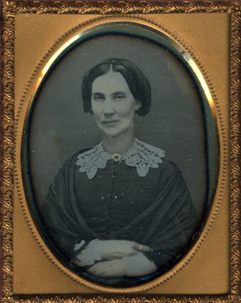 Ninth plate daguerreotype of Betsy H. Smith. Mrs. Smith was the mother of Rosellah M. Bowman and the grandmother of E.B. Harper. The portrait is a bust figure with the subject facing front. She is wearing a lace collar and shawl. Hand-coloring on cheeks, and gold details on a collar pin and a ring on her finger.