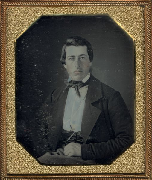 Sixth plate daguerreotype of an unidentified member of the Ingersoll family. The portrait is a half figure, front facing; the subject is seated with his hands resting in his lap. Hand-coloring on cheeks and lips.