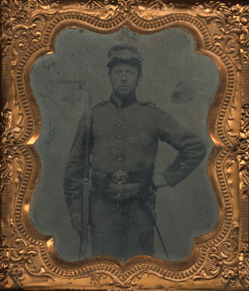 Sixth plate ferrotype/tintype of Burnett Demarest, a First Lieutenant in the Wisconsin 8th infantry, Co. C. Demarest mustered into service in 1861 at Eau Claire and served with the 8th regiment until the end of the war in 1865. The portrait is three-quarter length standing. Demarest is holding his rifle in his right hand and his other hand on his hip.