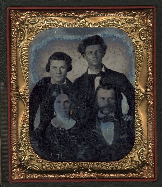 Sixth plate ambrotype of S.S. Pratt, his wife, and their two sons, Marcus on the right, and Phineus Warren on the left. Pratt and his wife are seated half figures, with sons standing behind. Gold details on the men's shirt buttons and the wife's watch chain and jewelry.