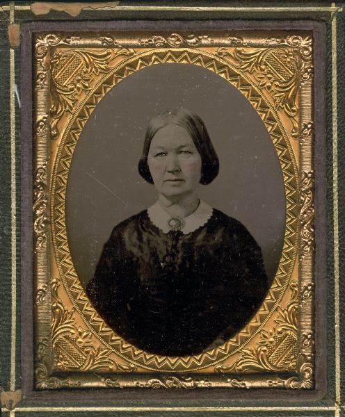 Ninth plate ambrotype of Mrs. Daniel Wells, Jr., of Milwaukee, Wisconsin. Half figure facing front, wearing white collar and a brooch at its center. Hand-coloring on cheeks and lips. 