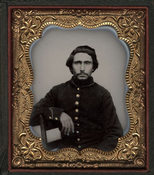 Sixth plate ferrotype/tintype of Israel W. Young. Seated half figure facing front with right arm resting on chair back, wearing beard and moustache. In Civil War uniform. Hand-coloring on cheeks and gold details on buttons. 