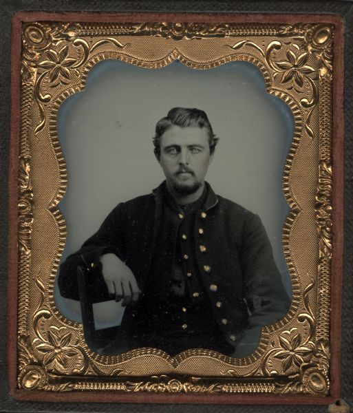 Sixth plate ferrotype/tintype of Chester D. Holloway. Seated half figure facing front, right arm resting on chair back, wearing Civil War uniform. Subject has beard and moustache. Hand-coloring on cheeks and gold details on buttons.