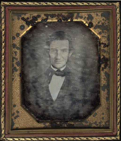 Sixth plate daguerreotype of William M. Dennis, Wisconsin Bank Comptroller from 1854-1858. Half figure facing front, wearing suit and tie with right tail of tie long and laying on coat lapel. Subject has long sideburns and beard under chin. 