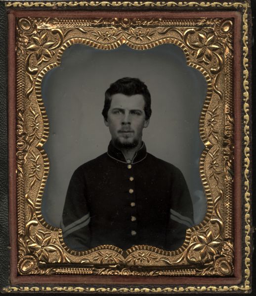 Sixth plate ferrotype/tintype. Waist-up portrait of Leander S. Miller, facing forward. Corporal in Civil War uniform. Hand-coloring on cheeks, gold details on buttons.