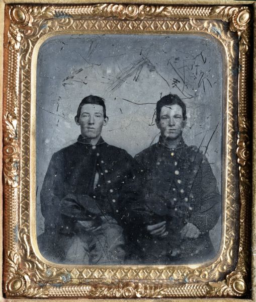 Sixth plate ferrotype/tintype of William H. Cheney (?) and Lyman Richardson. Half length portrait, seated, facing forward, wearing their Civil War uniforms with only the top button closed, and holding their caps. Hand-coloring on cheeks, and buttons of coat.