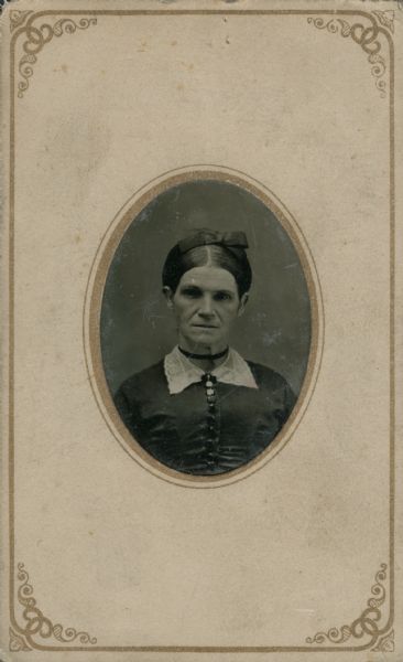 Ninth plate ferrotype/tintype quarter-length portrait of Mrs. Crandall, pioneer settler of Sheboygan Falls. She is wearing a dark dress with a white lace collar, a ribbon around her neck and a ribbon in her hair.