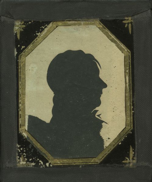Aperture-type silhouette cut from ivory colored paper on black ground of unidentified man. Subject faces right (proper left) wearing a tie and ruffled shirt, with loose hair over his forehead. 