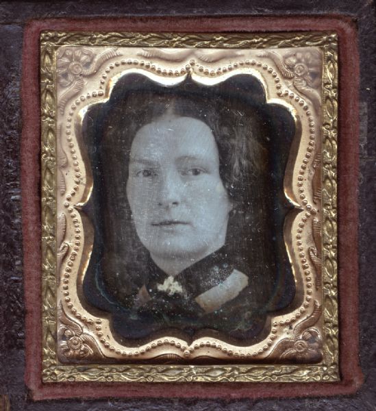 A sixteenth plate daguerreotype of Agnes Sharp. The portrait is a full facing view of her head. Hand-coloring of gold details on choker.