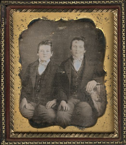 Sixth plate daguerreotype of James Day (left) and an unidentified boy, possibly Lionel Warrington Day. Three-quarter length portrait, seated, facing forward, wearing identical suits, striped vests and ties. The forearm of the boy on the right rests on a cloth covered table. Hand-coloring on cheeks.